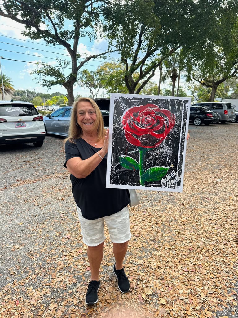 A Pap Corps guest holding the rose painting she bought at the Boca Polo Club gala