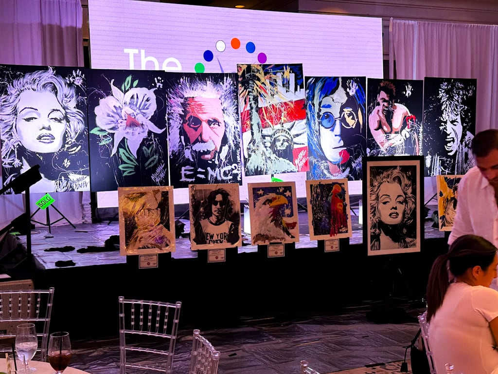 Michael Israel canvases lined up on stage at Boca Polo Club with a SOLD tag beside one of them