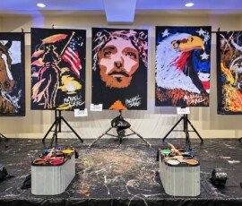 Five Michael Israel paintings on easels: a horse, a cowboy with the American flag, Jesus, an eagle, and a bull rider